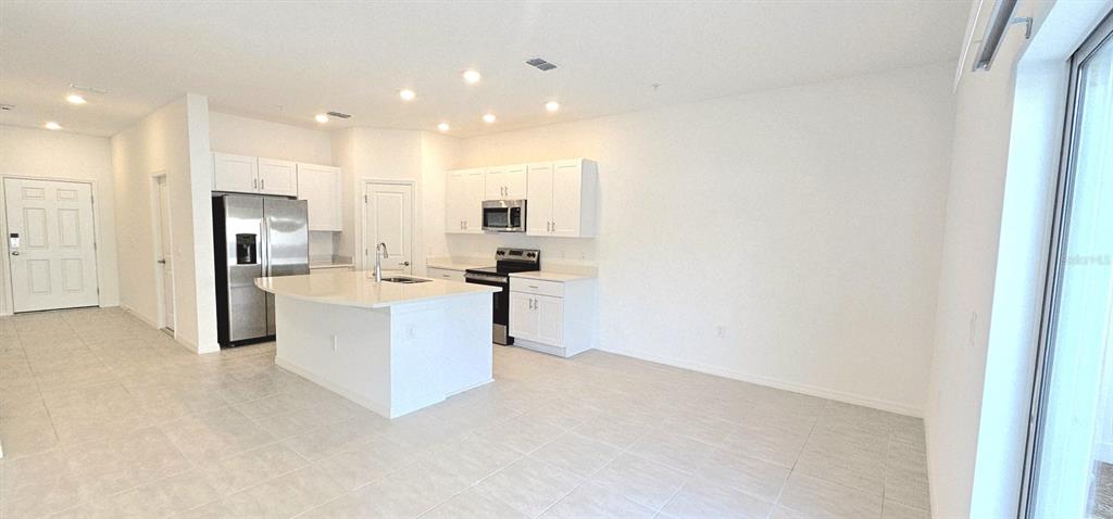 5000 Revolutionary Way St. Cloud, FL 34769 - Photo 17 of 32 a large white kitchen with kitchen island a sink a stove and a refrigerator