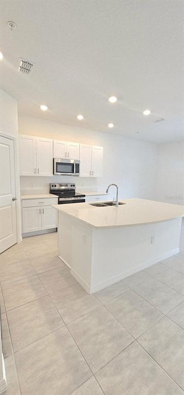 5000 Revolutionary Way St. Cloud, FL 34769 - Photo 8 of 32 a large white kitchen with kitchen island a sink stainless steel appliances and cabinets