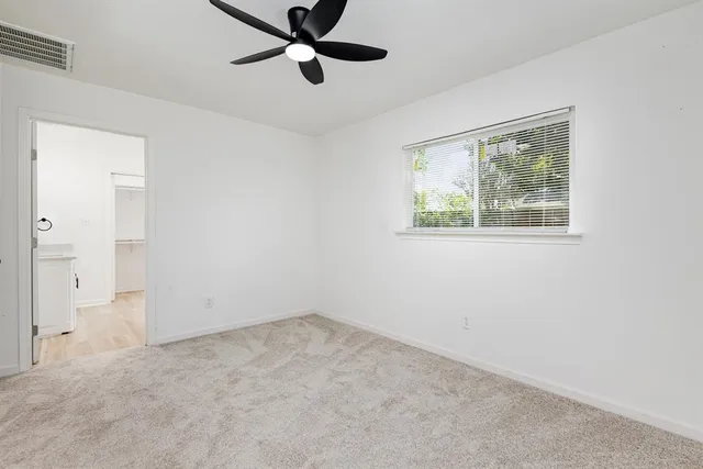 an empty room with a window and a fan