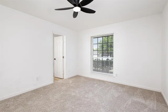 an empty room with ceiling fan and window