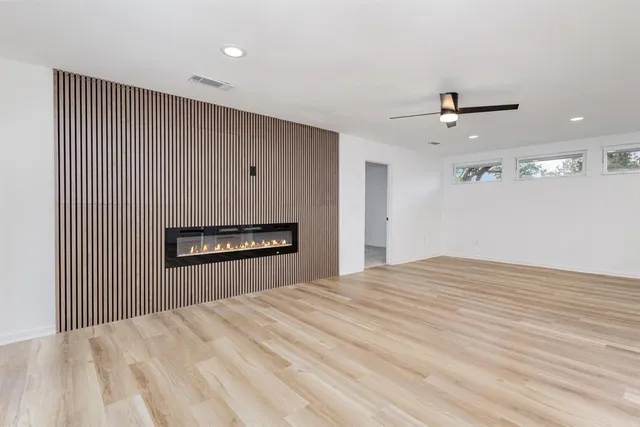 a view of an empty room with a window and a kitchen
