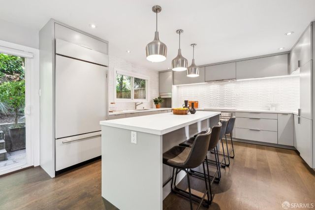 a kitchen with stainless steel appliances a dining table chairs refrigerator and sink