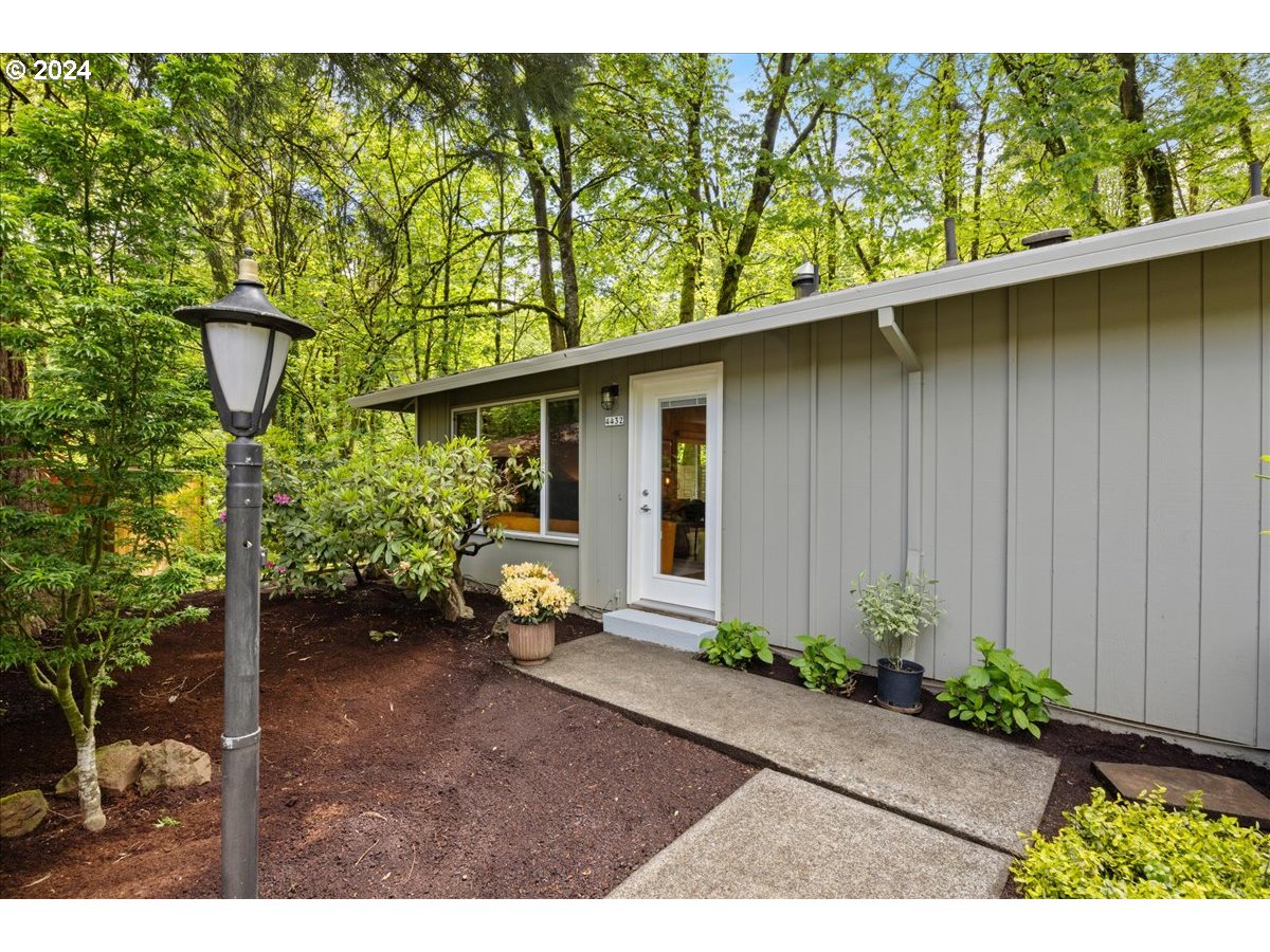 4432 Northwest Barnes Road Portland, OR 97210 - Photo 2 of 36 a backyard of a house with plants and trees with wooden fence