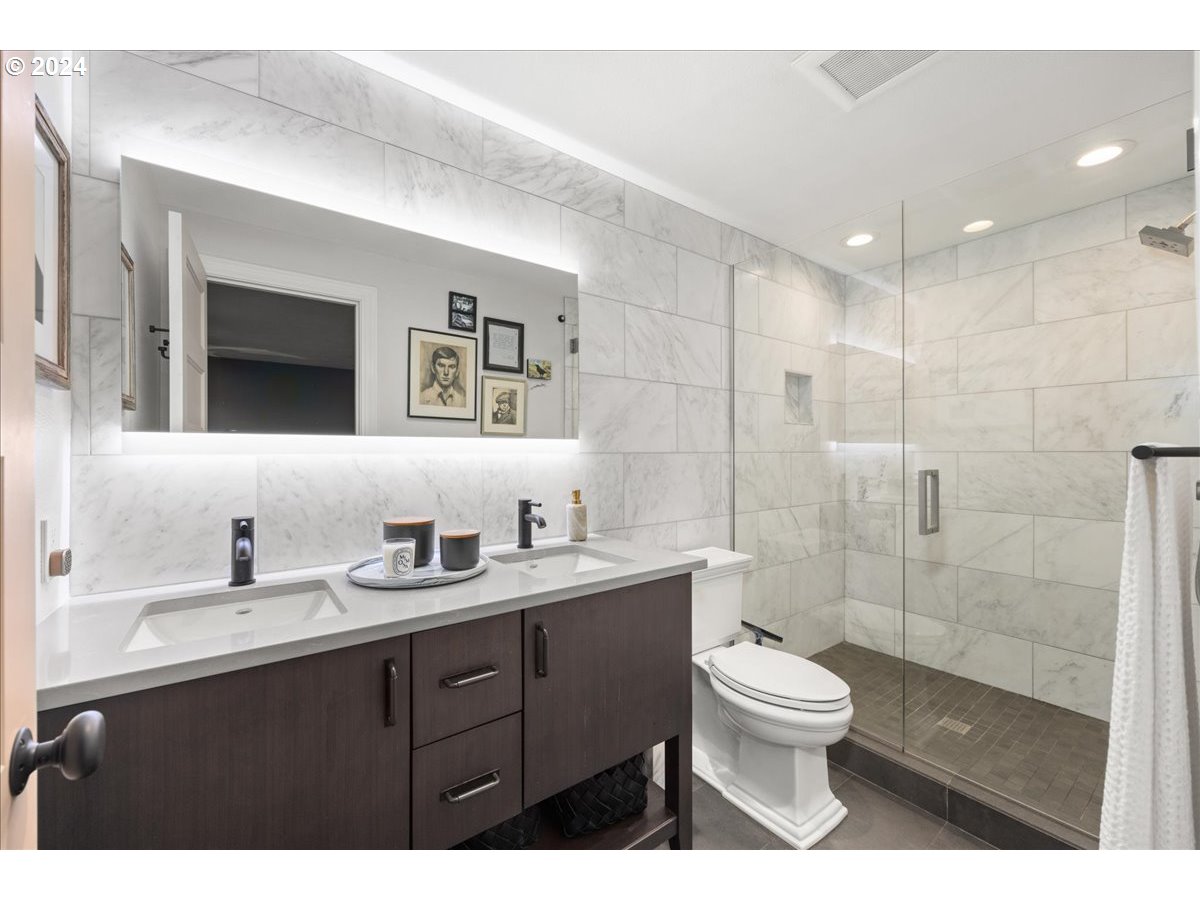 4432 Northwest Barnes Road Portland, OR 97210 - Photo 24 of 36 a bathroom with a double vanity sink toilet mirror and shower