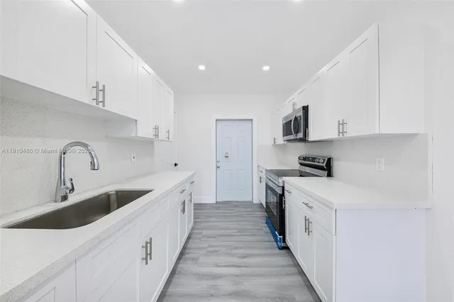 a kitchen with white cabinets sink and stainless steel appliances