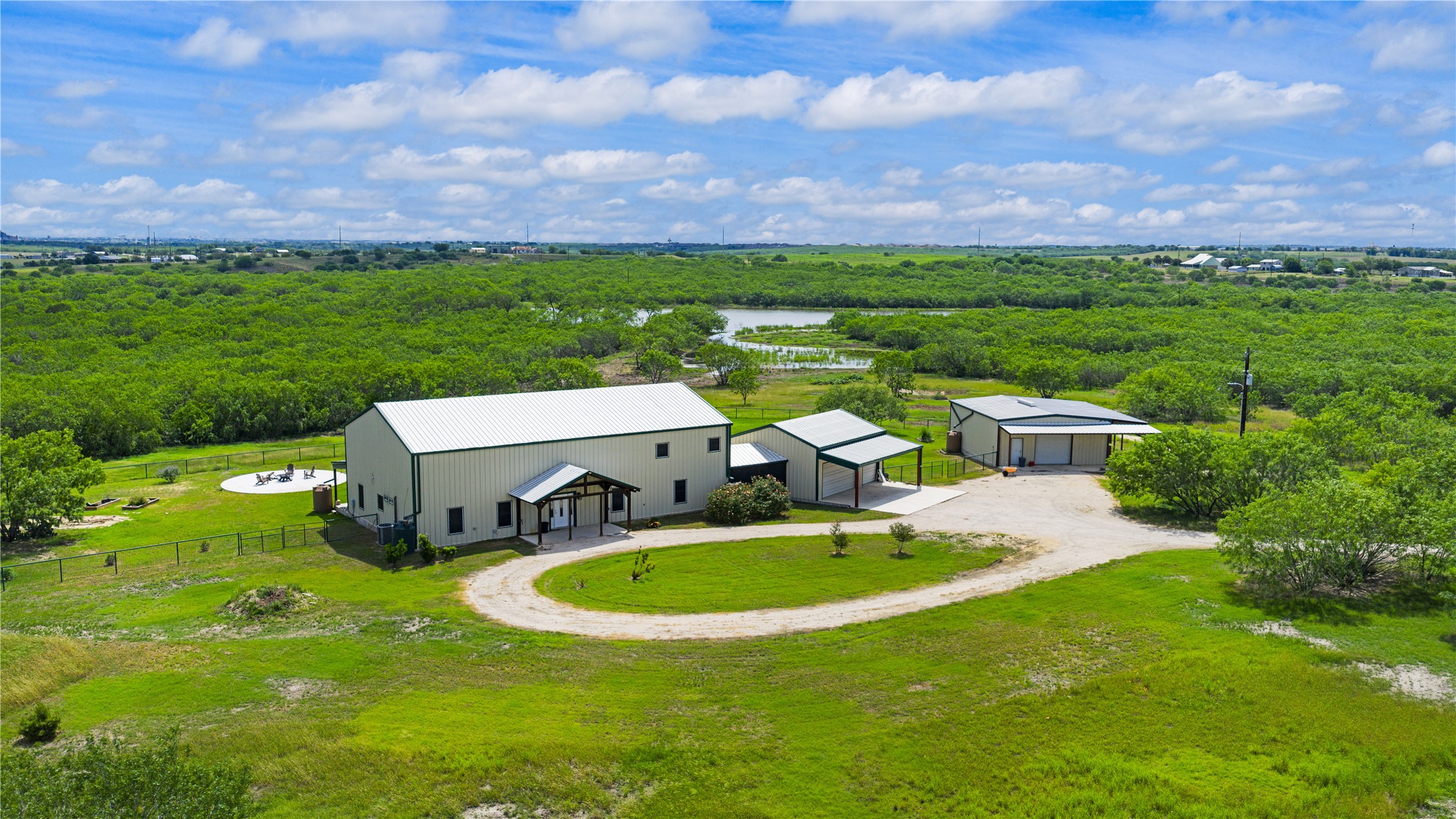 1293 Pioneer Road Seguin, TX 78155 - Photo 1 of 40 A spacious home with a separate garage and carport is nestled amidst a vast, verdant landscape with a serene pond.