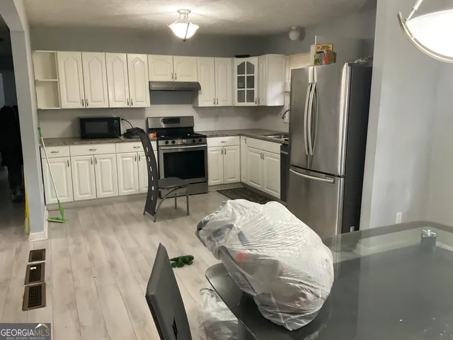 a kitchen with granite countertop a refrigerator stove and wooden floor
