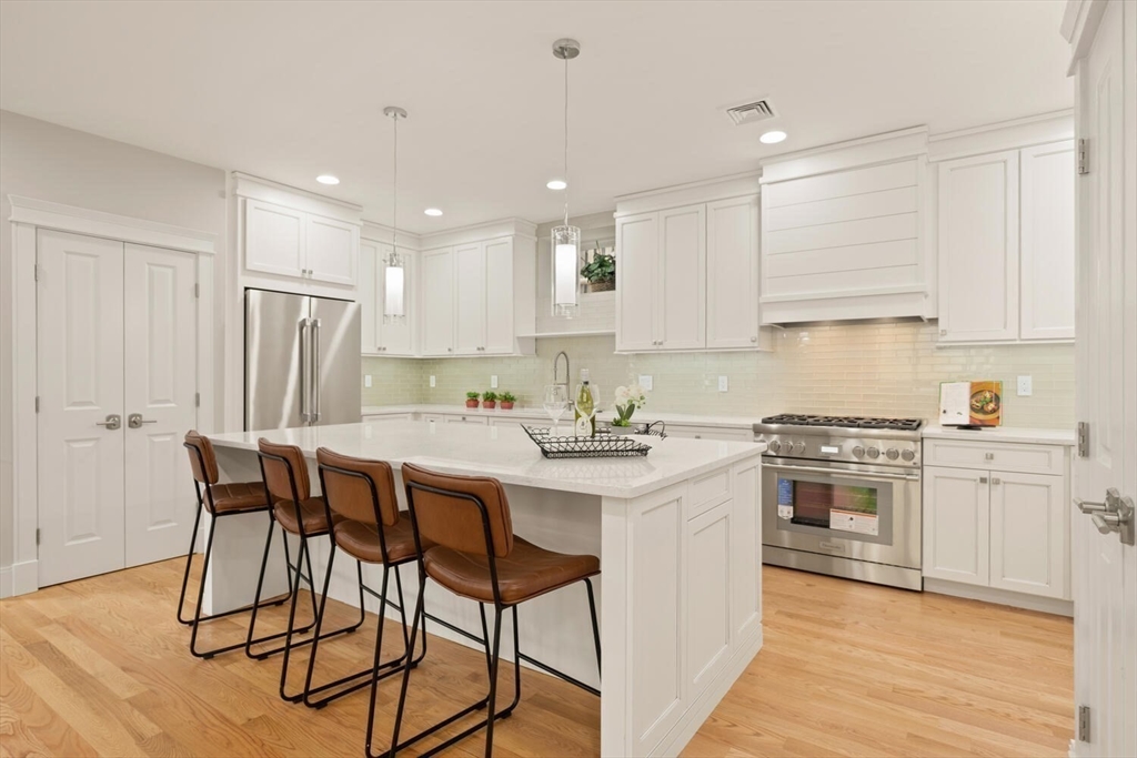 7 Whitman Street, Unit 1 Somerville, MA 02144 - Photo 2 of 35 a kitchen with stainless steel appliances granite countertop a table chairs sink refrigerator and cabinets