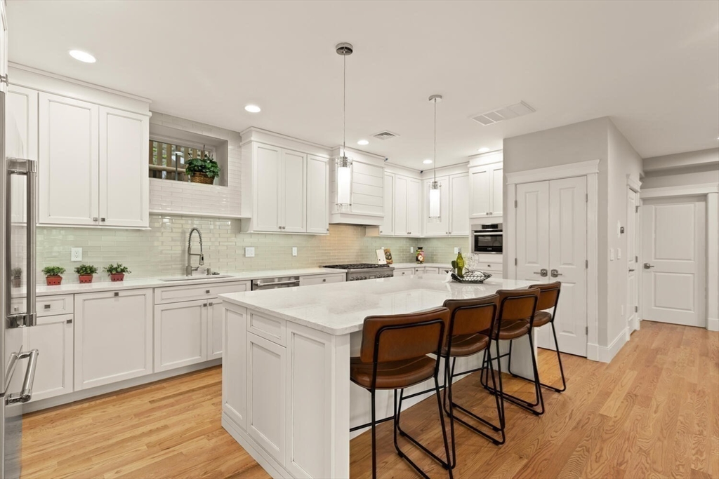7 Whitman Street, Unit 1 Somerville, MA 02144 - Photo 5 of 35 a kitchen with a sink a center island cabinets and a window