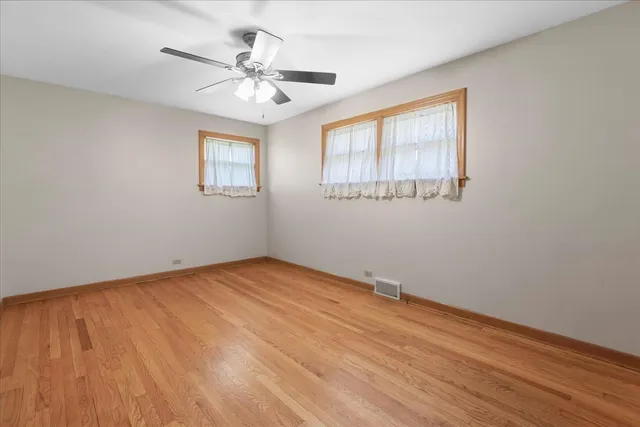 a view of an empty room with a window and a chandelier fan