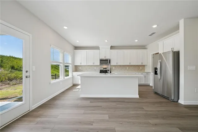 a large white kitchen with white cabinets and wooden floor