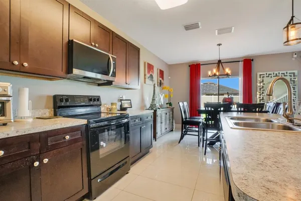 a kitchen with stainless steel appliances granite countertop a stove top oven a sink a dining table and chairs with wooden floor