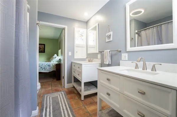 a en suite bathroom with a double vanity sink a mirror and next to a window