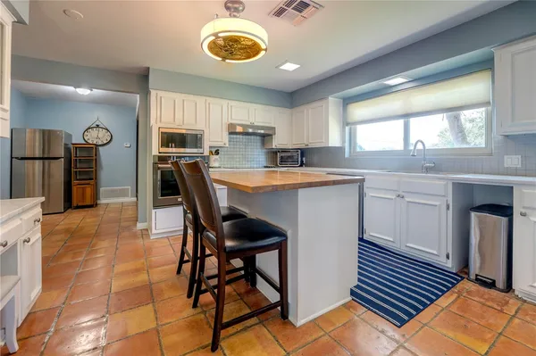 a kitchen with stainless steel appliances a stove a sink cabinets and a dining table