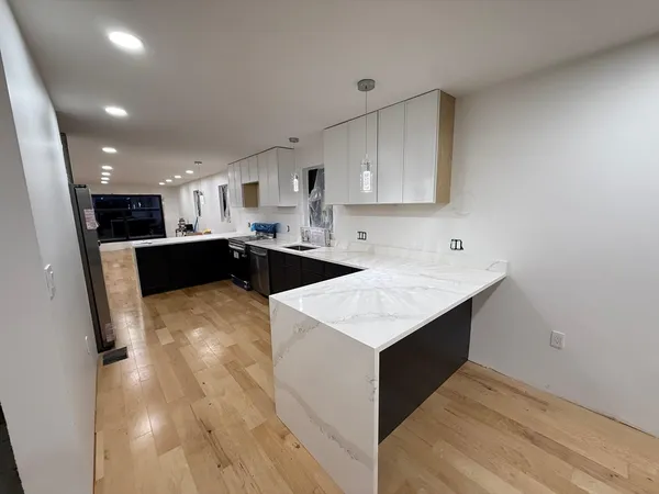 a room with kitchen island a sink wooden floor and glass door