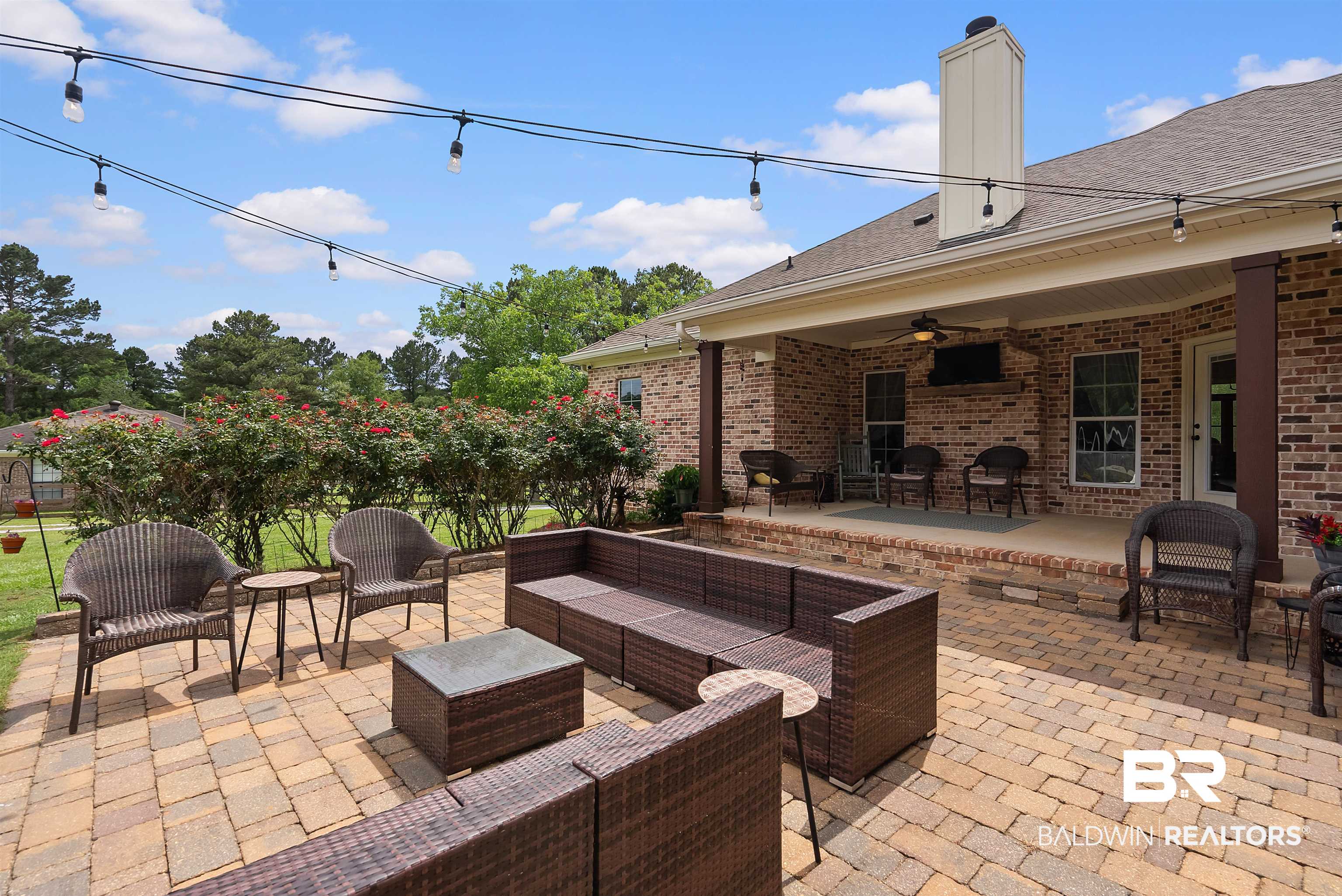 12070 Comalander Road Fairhope, AL 36532 - Photo 41 of 50 Expansive paver patio with string lighting and brick house exterior