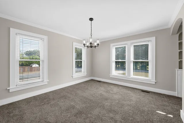 a view of empty room with a chandelier fan and windows