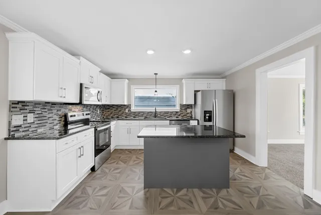 a kitchen with stainless steel appliances granite countertop a refrigerator a sink dishwasher a stove and white countertops with wooden floor