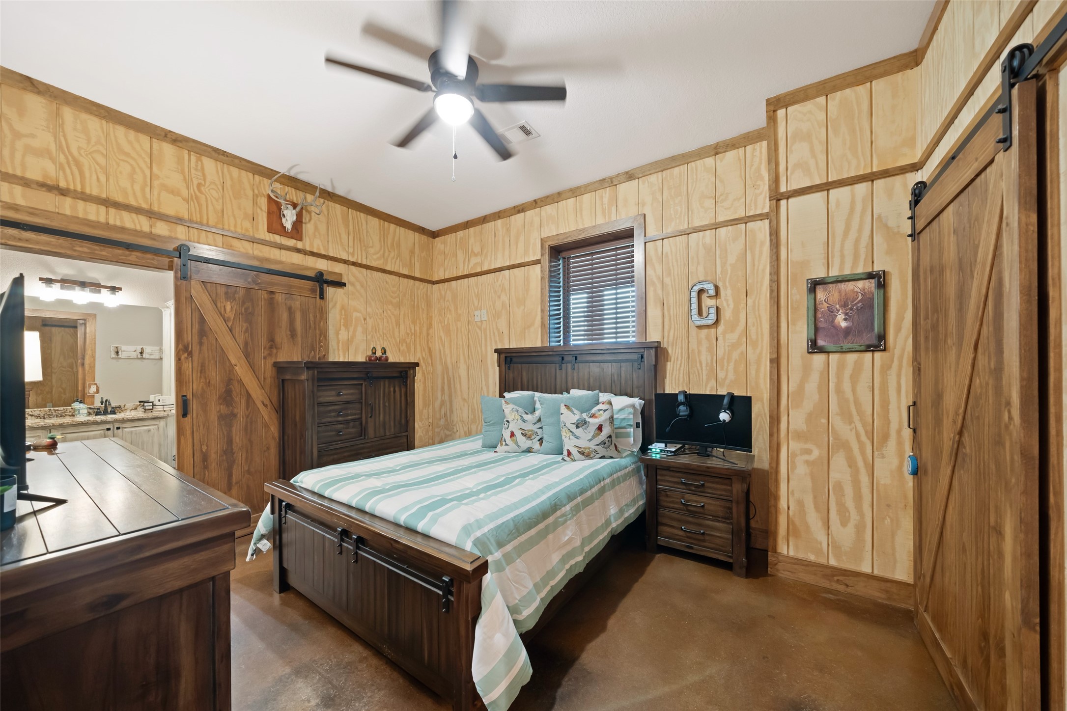 1402 Eagle Ferry Road Anahuac, TX 77514 - Photo 38 of 48 Bedroom includes sliding barn door closet access, rustic trim details, and ceiling fan.