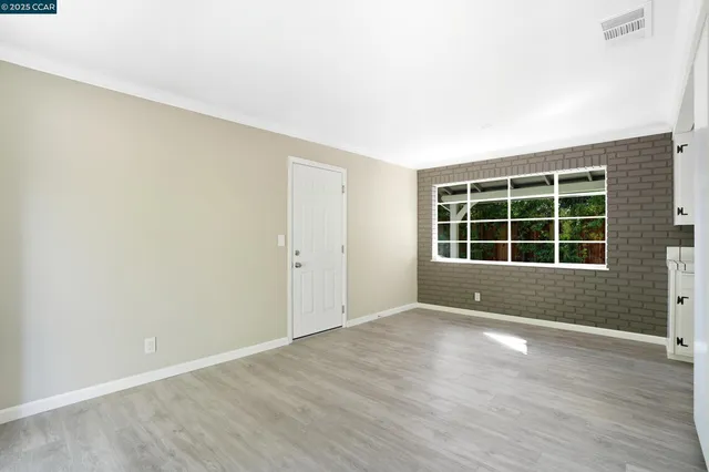 an empty room with wooden floor fireplace and windows