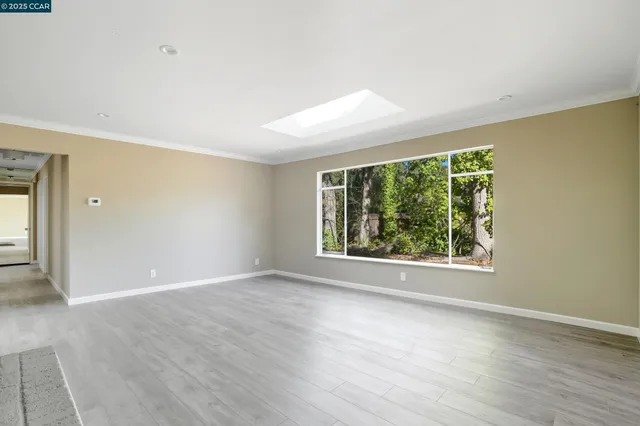 a view of an empty room with wooden floor and a fireplace