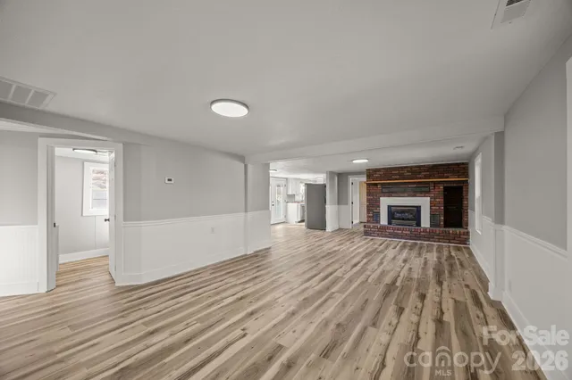 a view of empty room with wooden floor and fireplace