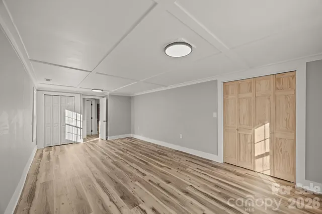 a view of empty room with wooden floor and fan