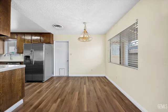 a kitchen view with wooden floor a refrigerator and a window