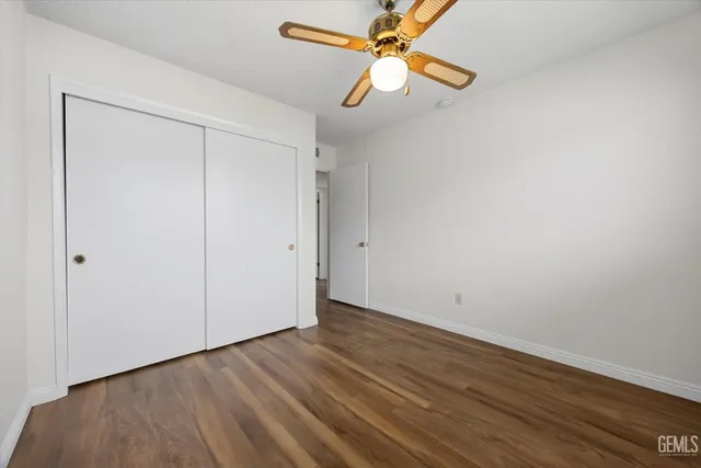 an empty room with wooden floor closet and fan