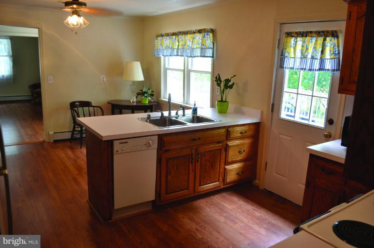 3355 Uniontown Road Westminster, MD 21158 - Photo 2 of 21 a kitchen with a sink cabinets wooden floor and a dining table