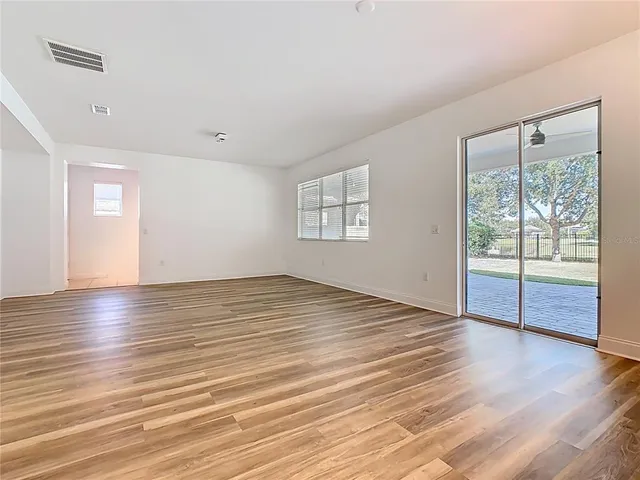 an empty room with wooden floor and a ceiling fan