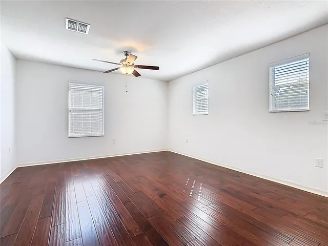 an empty room with wooden floor and windows