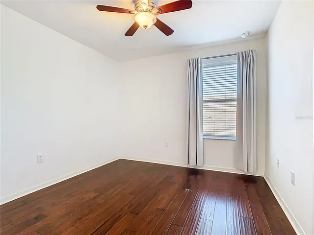 a view of an empty room with window and wooden floor