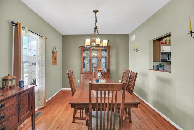 a dining room with wooden floor a chandelier a wooden table and chairs