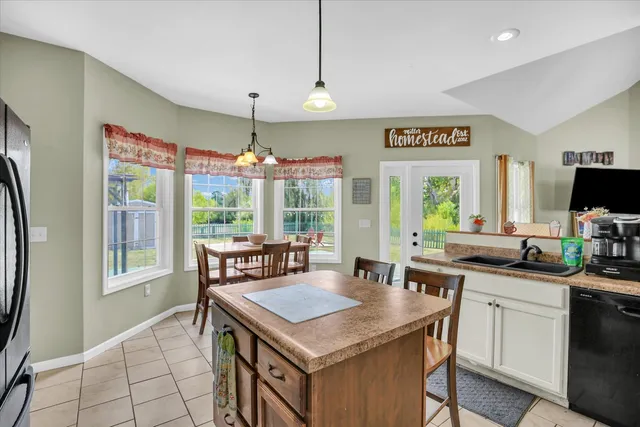 a kitchen with stainless steel appliances granite countertop a stove refrigerator and a dining table with chairs