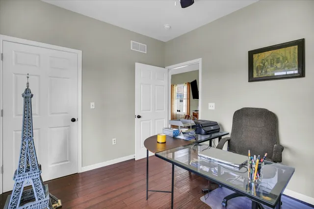 an empty room with wooden floor ceiling fan and windows