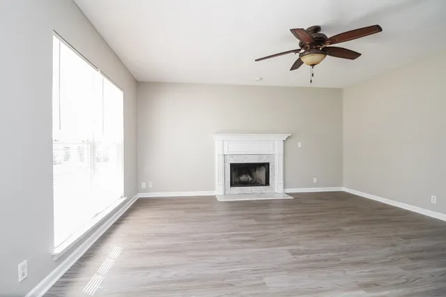 a view of empty room with wooden floor and fan