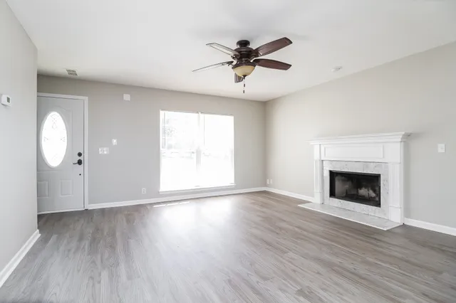 an empty room with wooden floor fan and windows