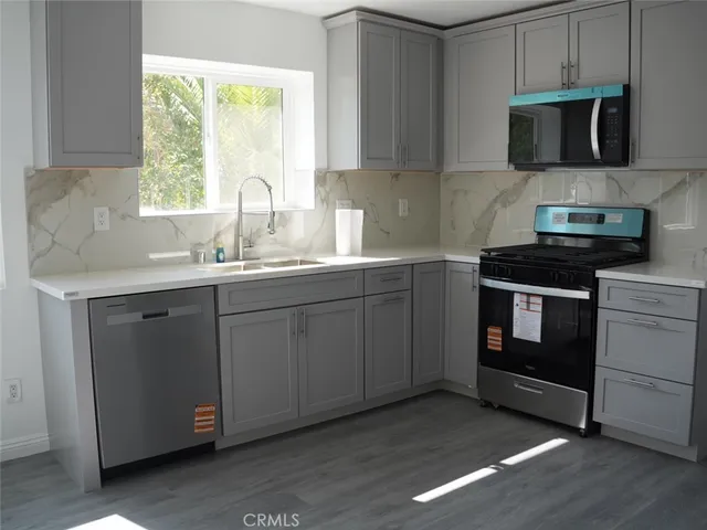 a kitchen with stainless steel appliances granite countertop a stove a sink and a microwave