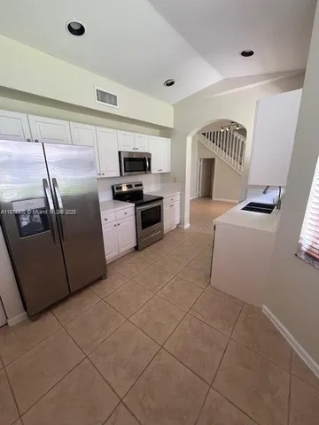 a kitchen with granite countertop a refrigerator and a stove top oven