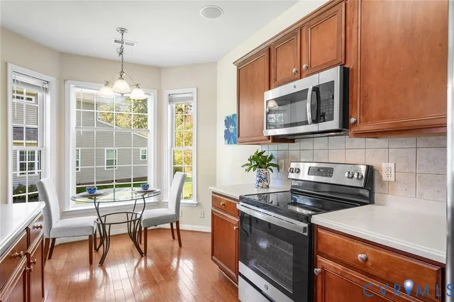 a kitchen with stainless steel appliances granite countertop a refrigerator a sink dishwasher and wooden cabinets with wooden floor