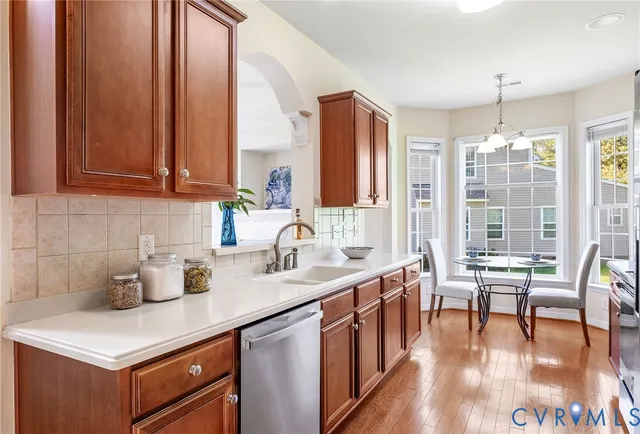 a kitchen with stainless steel appliances granite countertop a refrigerator a stove a sink a dining table and chairs with wooden floor