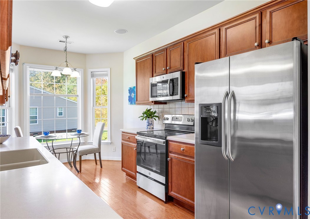 13532 Baycraft Terrace Midlothian, VA 23112 - Photo 10 of 28 a kitchen with stainless steel appliances granite countertop a refrigerator a stove a sink a dining table and chairs with wooden floor