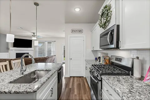 a kitchen with granite countertop a sink a stove and a wooden floor