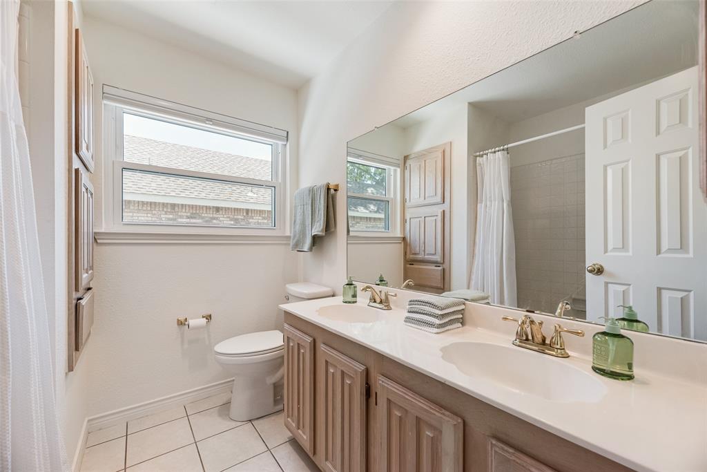 1406 West Peters Colony Road Carrollton, TX 75007 - Photo 15 of 29 a bathroom with a double vanity sink toilet and a mirror