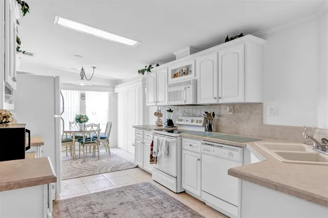 a kitchen with a sink white cabinets and white appliances