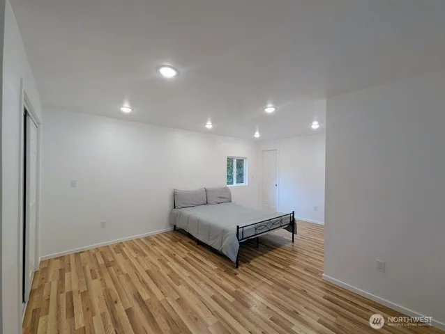 a spacious bedroom with a bed and a wooden floor