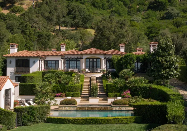 a front view of a house with a garden and trees