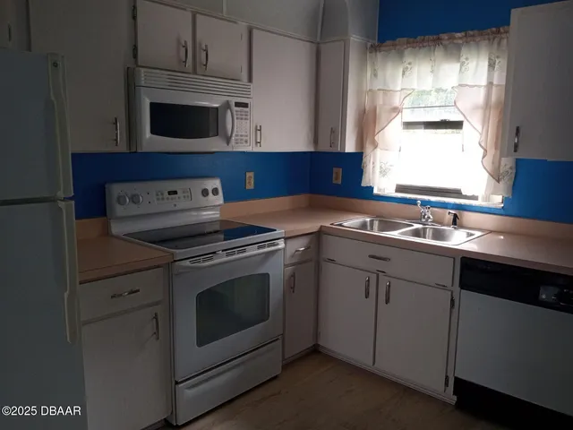 a kitchen with granite countertop white cabinets and white appliances
