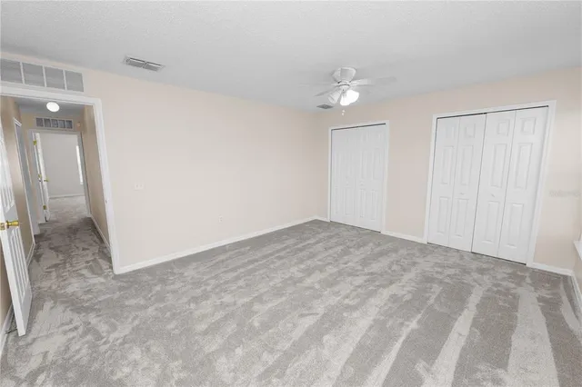 an empty room with a window and a fan